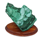 Malachite mineral specimen on a wooden stand against a white background