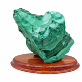 Malachite mineral specimen on a wooden base against a white background